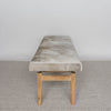 end view of a gray and caramel hide on a cowhide bench seat secured to a teak wood base by Corcovado Designs