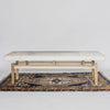 front view of a Corcovado Design creamy white cowhide bench seat with wooden legs on a vintage turkish rug