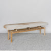 angled view of Corcovado Design's cowhide ottoman bench which featuring caramel and cream shades on top of a looped rug.