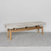 angled view of Corcovado Design's cowhide ottoman bench which featuring cream and gray tones on top of a looped rug.