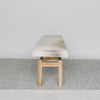 end view of Corcovado Design's cowhide ottoman bench which featuring cream and gray tones on top of a looped rug.