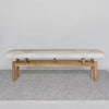 front view of Corcovado Design's cowhide ottoman bench which featuring cream and gray tones on top of a looped rug.