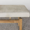 close up view of Corcovado Design's cowhide ottoman bench which featuring cream and gray tones on top of a looped rug.