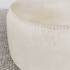 close up of the leather stitching along the top of the light colored hair on hide ottoman coffee table