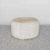 light colored cowhide ottoman coffee table with small teak wood feet on a gray colored looped rug