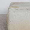 close up showing the leather hand stitching on the light creamy colored square hide ottoman coffee table