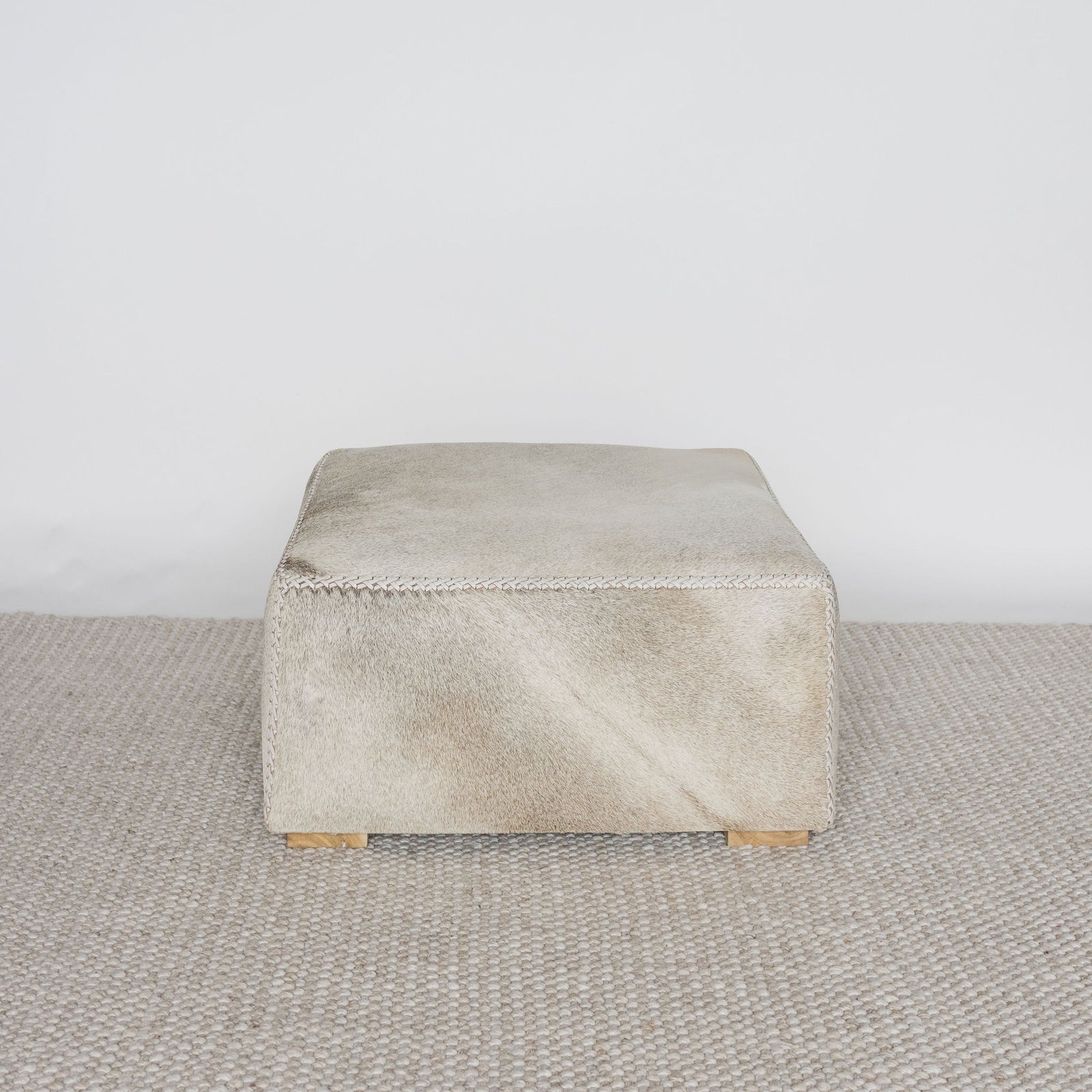 square cowhide coffee table ottoman in earthy tones and gray by corcovado design