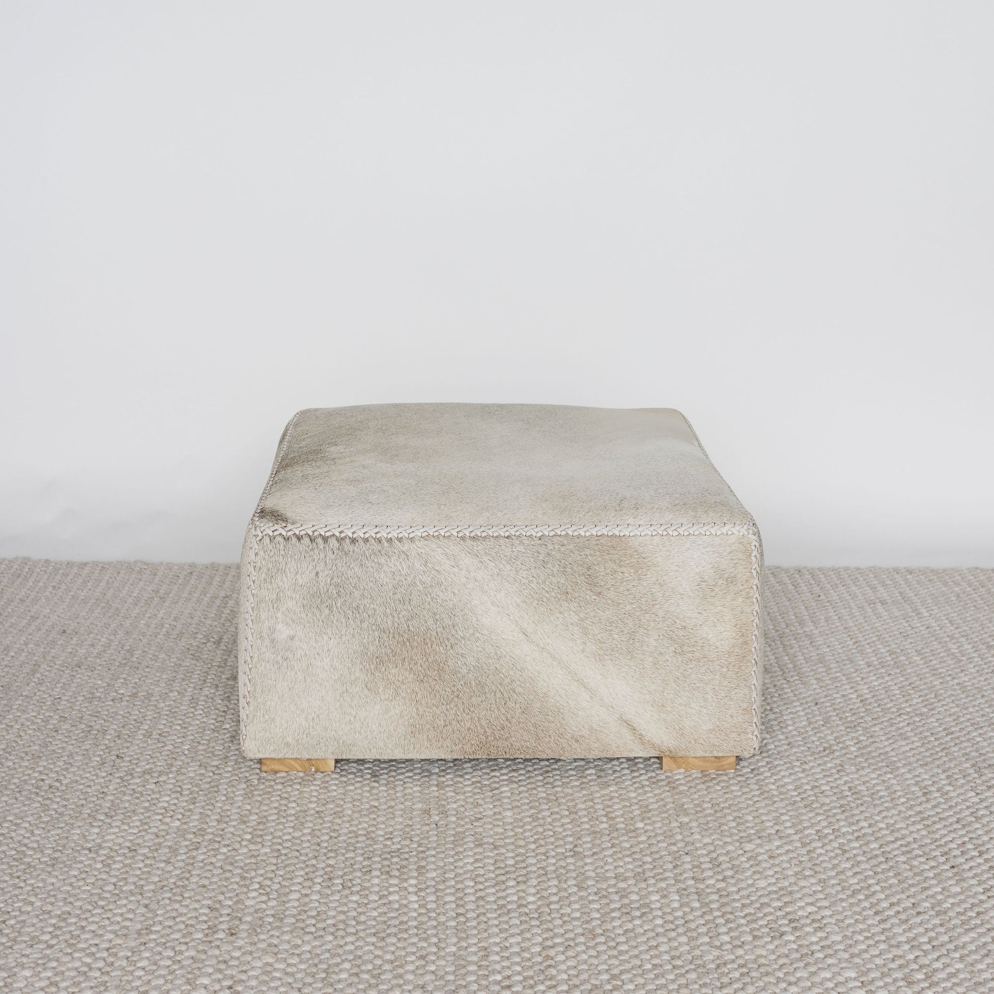 square cowhide coffee table ottoman in earthy tones and gray by corcovado design