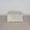 front view of the square creamy colored cowhide ottoman coffee table