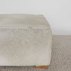 close up view of the square creamy colored cowhide ottoman coffee table