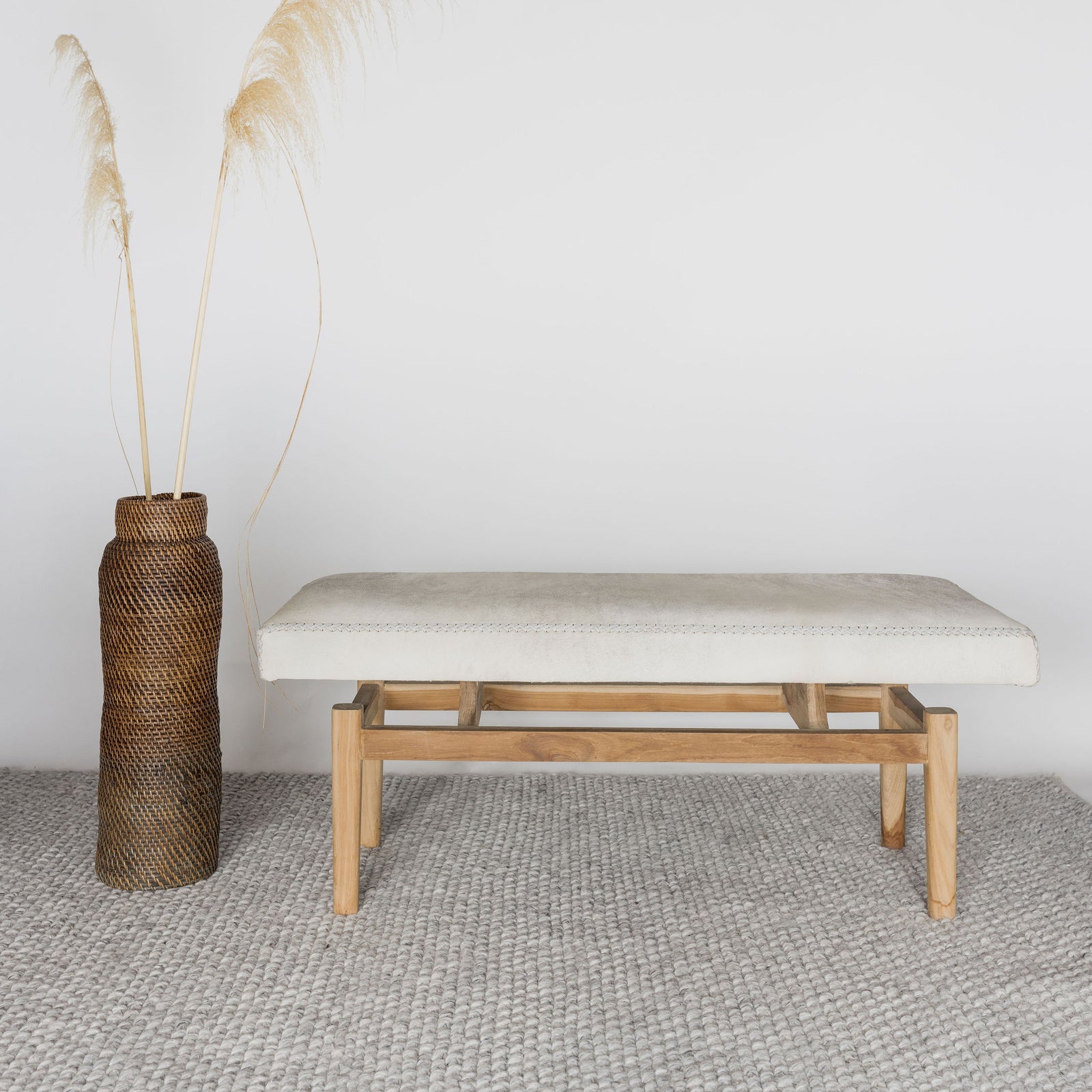 cream and gray colored hide ottoman bench by Corcovado next to a vintage brown woven tall basket 