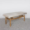 angled view of  cowhide ottoman bench seat on a teak wood base