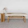 front view of a caramel and cream colored hair on hide bench seat for entry or bedroom bench next to a small wooden side table and vase with faux flowers