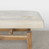 end view of a light cream colored hide ottoman bench