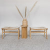 set of two small cowhide bench seats in caramel brown and white hide with a small table and basket on top of the table