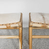 close up view of the two benches that make up the set of two small cowhide bench seats in caramel brown and white hide