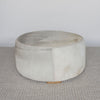 extra large round hair on hide ottoman coffee table with leather stitching and small teak wood feet on a grey and white rug