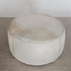 top view of front view of a light colored hair on hide round ottoman coffee table by corcovado design