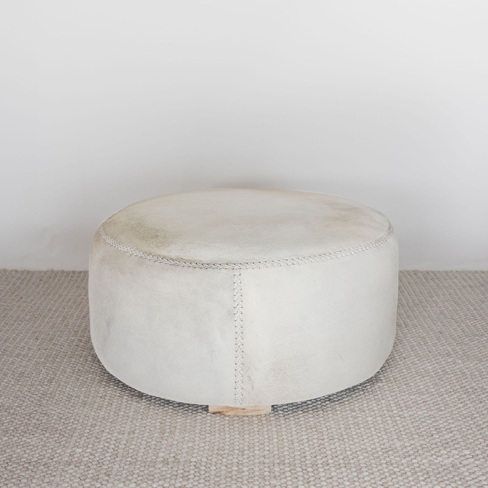 front view of a light colored hair on hide round ottoman coffee table by corcovado design 