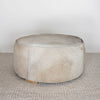 natural toned round hide footstool with leather stitching