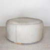 natural toned round hide footstool with leather stitching