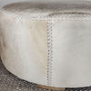 close up of the natural toned round hide footstool with leather stitching