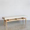 angle view of the wide cream boucle upholstered bench seat ottoman for entry or bedroom bench