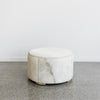 cream colored light round cowhide ottoman coffee table with a grey fleck through the hide