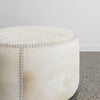 close up view of the cream colored light round cowhide ottoman coffee table