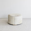 side view of the round creamy hide ottoman coffee table