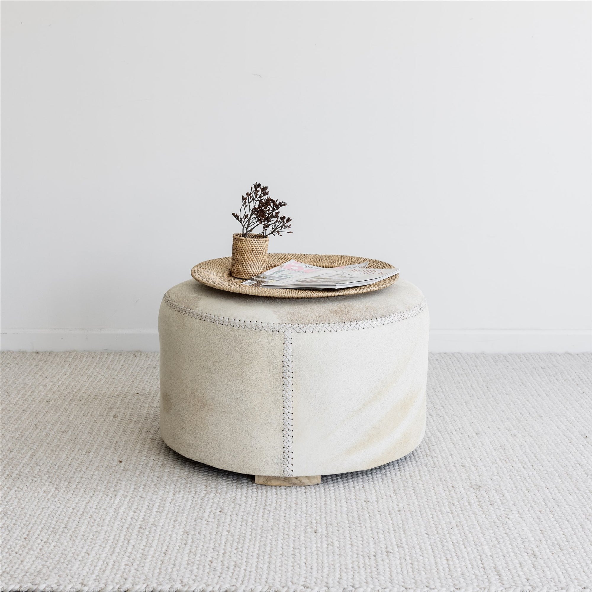 round cowhide ottoman coffee table with a natural rattan tray on top