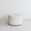 side view of the leather stitching on the creamy colored cowhide ottoman