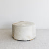 side view of the brown and cream round cowhide ottoman coffee table