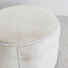 close up angle of the creamy light toned cowhide ottoman coffee table  showing the leather hand stitching