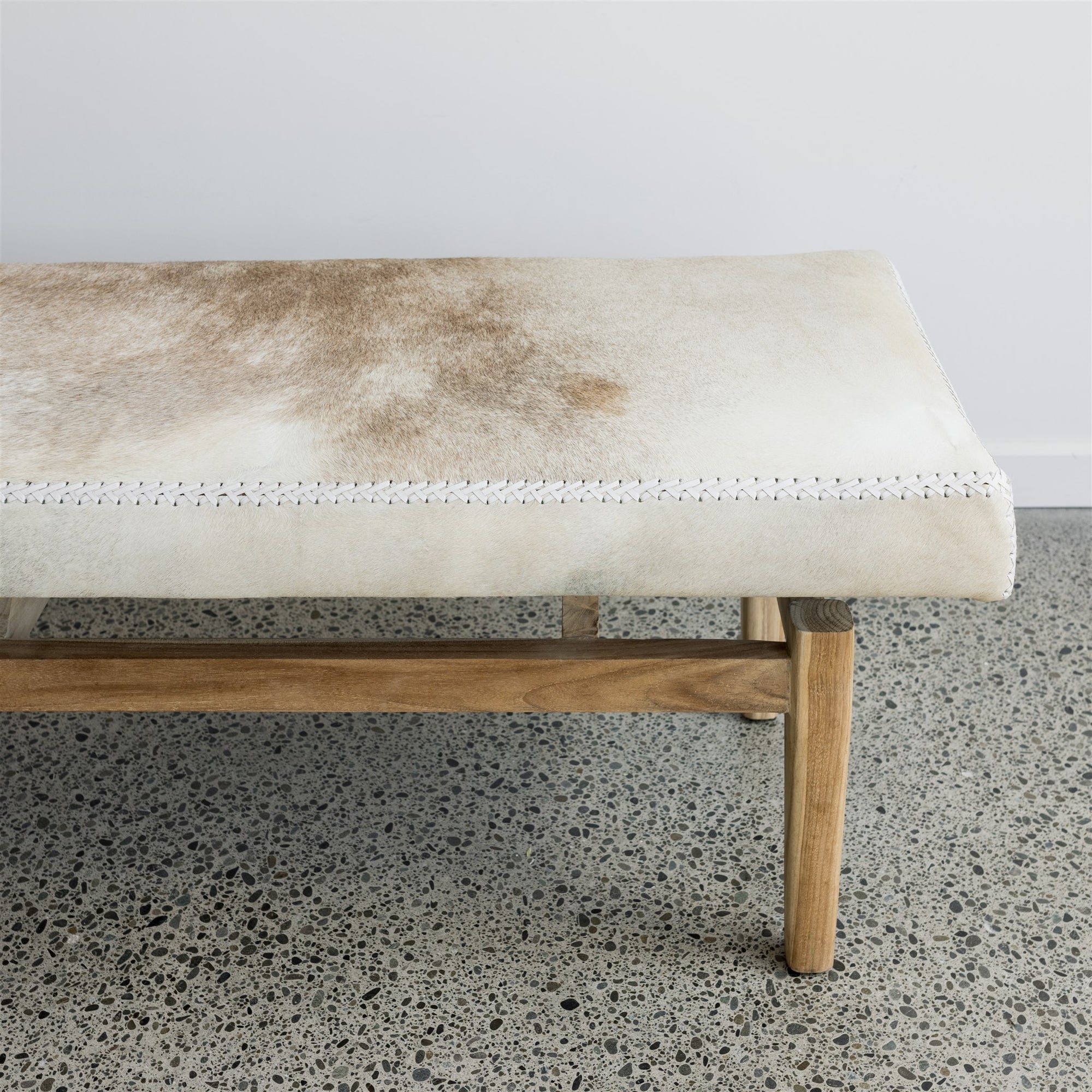 close up of the brown and cream cowhide bench seat ottoman for a window seat