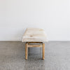 end view  of the brown and cream colored cow hide bench seat ottoman