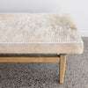 close up showing the cowhide on the brown and cream colored cow hide bench seat ottoman