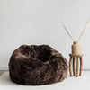 dark brown sheepskin beanbag chair with small wooden side table