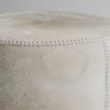 Detail of the leather stitching on Corcovado Designs round hide ottoman coffee table placed on a white looped floor rug