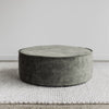 low round velvet ottoman in jade green velvet on a white area rug