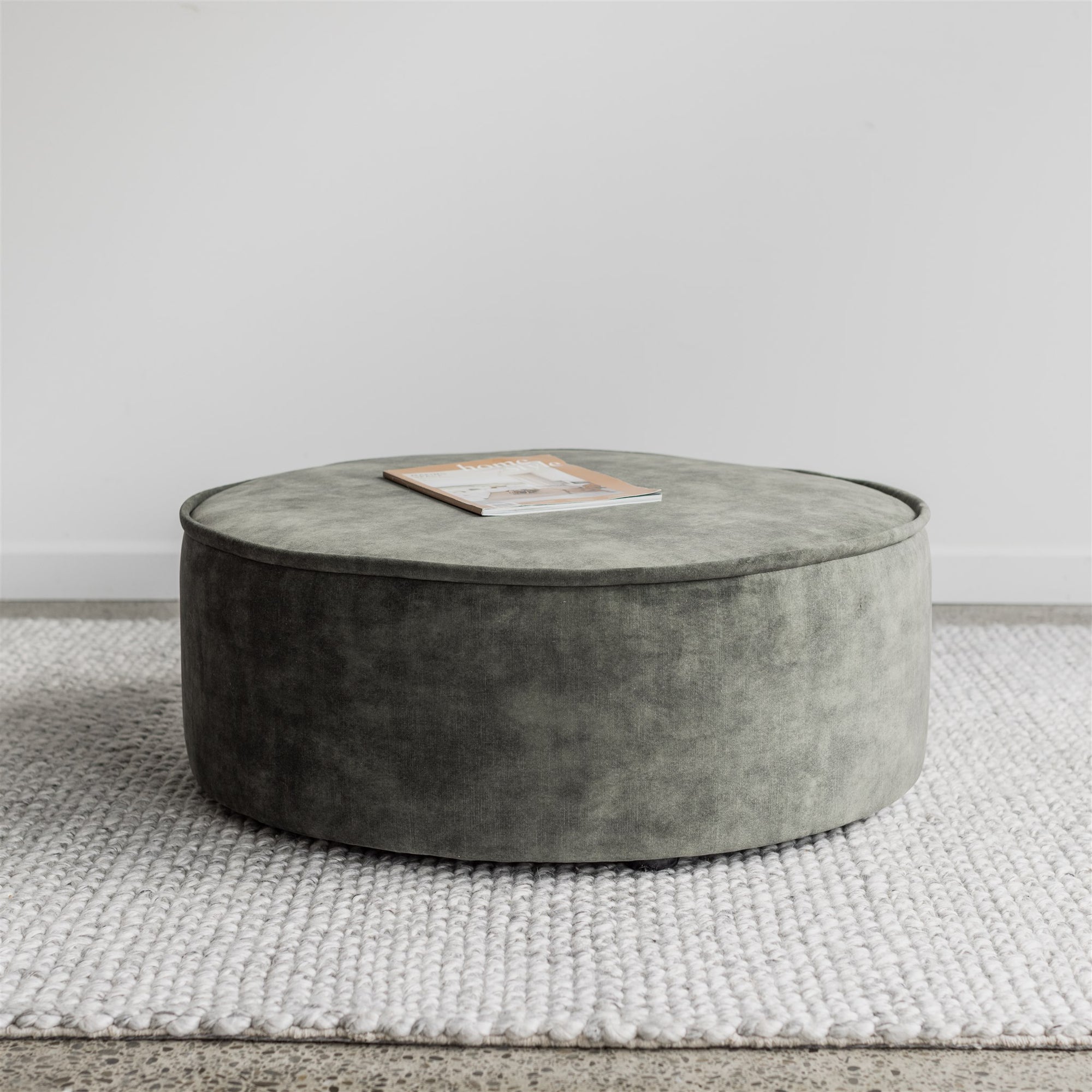 round ottoman in green velvet with piped edges