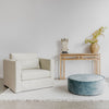 linen arm chair teak hallway sideboard and low, round velvet ottoman in a soft blue color