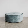 low, round velvet ottoman in a soft blue color