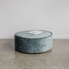 low, round velvet ottoman in a soft blue color