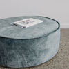 close up of low, round velvet ottoman in a soft blue color